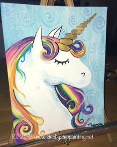 an easel with a painting of a unicorn's face and rainbow manes on it