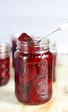 a jar filled with red liquid sitting on top of a wooden table next to other jars