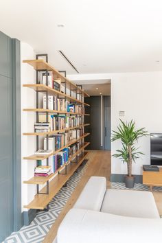 a living room filled with furniture and a large book shelf next to a tv on top of a hard wood floor