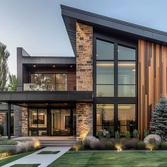 a large modern house with lots of glass and wood on the front door, along with landscaping