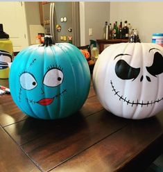 two painted pumpkins sitting on top of a wooden table