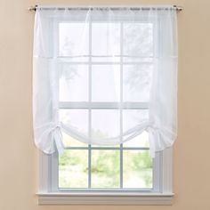 a window with white sheer curtains hanging from it's side