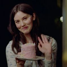 a woman holding a pink cake on top of a white plate