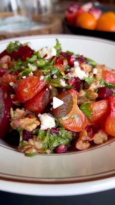 a white plate topped with salad next to oranges