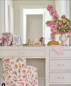 a white desk topped with a flower covered chair and a large mirror over it's top