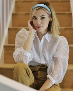 a woman is sitting on the stairs with her hand under her chin and looking at the camera