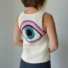 a woman wearing a crocheted tank top with an eye design on the back