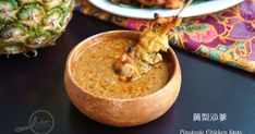 a wooden bowl filled with food on top of a table next to pineapples