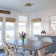 a dining room table with four chairs and a vase on the table in front of it