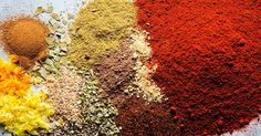 various spices and seasonings are arranged on a blue surface, including red, yellow, orange, and green