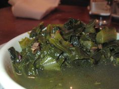 a white plate topped with greens on top of a wooden table