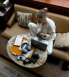 a woman is sitting on a couch with her laptop and headphones in her hands