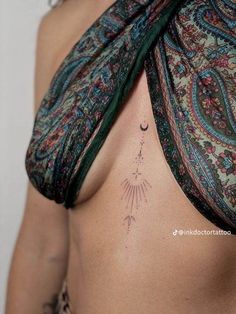 a woman's chest with an arrow tattoo on her left side ribcage