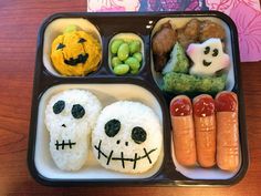 a bento box filled with rice, vegetables and fruit decorated to look like skeletons