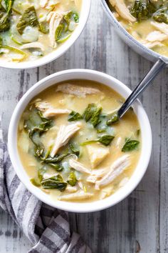 two bowls of chicken and spinach soup on a wooden table with a checkered napkin