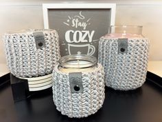 three crocheted jars with labels on them sitting next to a chalkboard sign