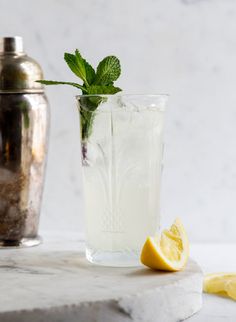 a glass filled with lemonade next to a silver shaker on a marble counter