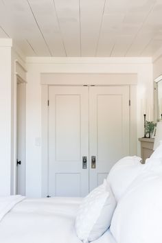 a bed with white sheets and pillows in a room