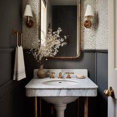 a bathroom sink sitting under a mirror next to a wall mounted faucet with lights on it