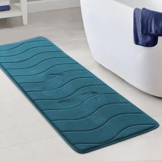 a blue bath mat sitting on top of a bathroom floor next to a white tub