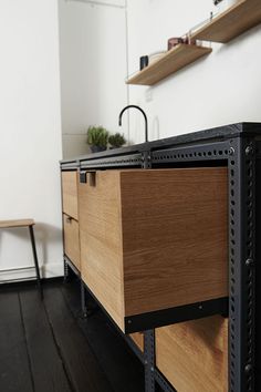 a wooden cabinet with metal handles on the bottom and drawers below it, in front of a white wall