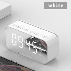 an alarm clock sitting on top of a table next to a cell phone