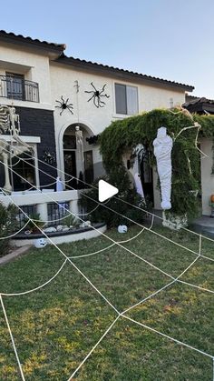 a house decorated for halloween with spider webs and fake skeletons on the front lawn