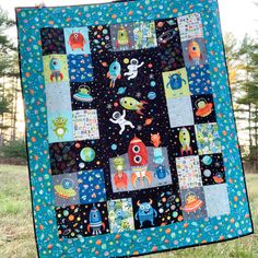 a quilted space themed wall hanging in the grass