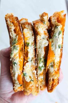 four pieces of bread with cheese and vegetables on them in the palm of someone's hand