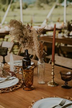 the table is set with plates, candles and vases