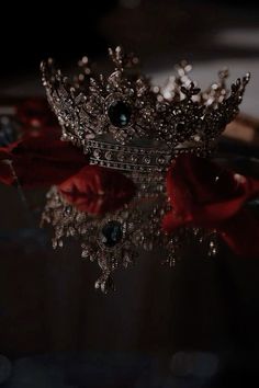 a crown sitting on top of a table next to a red rose with water droplets