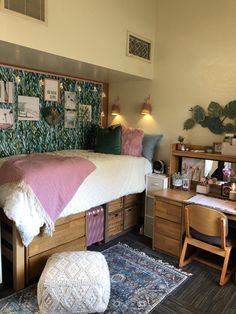 a bedroom with a bed, desk and chair next to a wall covered in plants