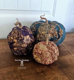 three decorative pumpkins sitting on top of a wooden table