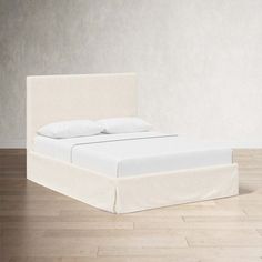 a white bed sitting on top of a hard wood floor