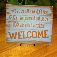 a welcome sign sitting on top of a wooden table next to a potted plant