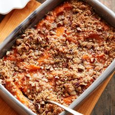 a casserole dish filled with meat and vegetables on top of a wooden table