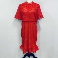 a red lace dress on a mannequin headdress with black shoes in the foreground