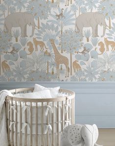 a baby crib with an elephant and giraffe wallpaper in the background