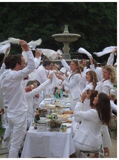 a group of people dressed in white standing around a table