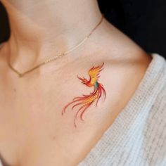 a woman's chest with a colorful bird tattoo on the left side of her neck