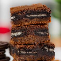 a stack of brownies sitting on top of each other next to oreo cookies