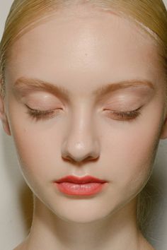 a woman with her eyes closed and pink lipstick in front of her face is looking down at the camera