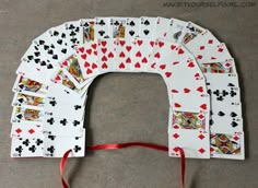 playing cards laid out in the shape of an arch with red ribbon around them on a gray surface