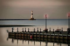 the light house is in the distance by the water