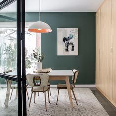 a dining room with green walls and wooden furniture in the center, along with a white rug on the floor