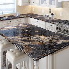 a kitchen with marble counter tops and white cabinets, along with stools for seating