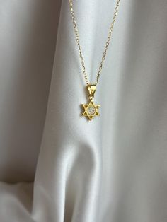 Tiny and so gorgeous, our Star of David charm is perfect for those that love small and dainty pieces! Information: ✨Sterling Silver (925 stamped) | 14K Gold Plated ✨High quality AAA+ Cubic Zirconia gemstones ✨Adjustable length: 16" - 18" ✨Hypoallergenic ✨Tarnish resistant Our Star of David charm necklace is minimalist and a classic, the necklace is made with great craftsmanship and attention to detail. Both the metals and the gemstones are highly polished for a beautiful sparkle! The charm is dainty, it measures .35" by .35" ( picture with ruler for reference ). The necklace is adjustable from 16" to 18", allowing you to find the perfect fit and create multiple layering styles. This makes a perfect gift. Star Of David Necklace Aesthetic, Gold Star Of David Charm Necklace For Gift, Luxury Star Of David Necklace With Star Charm, Gold Star Of David Necklaces, Elegant Star Of David Necklace, 14k Gold Star Of David Necklace, Tarnish Resistant, Jewish Star Necklace, Star Of David Necklace, Jewish Star