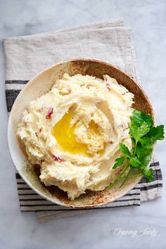 a bowl filled with mashed potatoes on top of a striped towel next to a fork