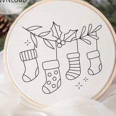 a hand embroidered christmas stocking ornament with stockings and holly leaves on it