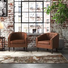 two brown chairs in front of a brick wall with a potted plant next to it